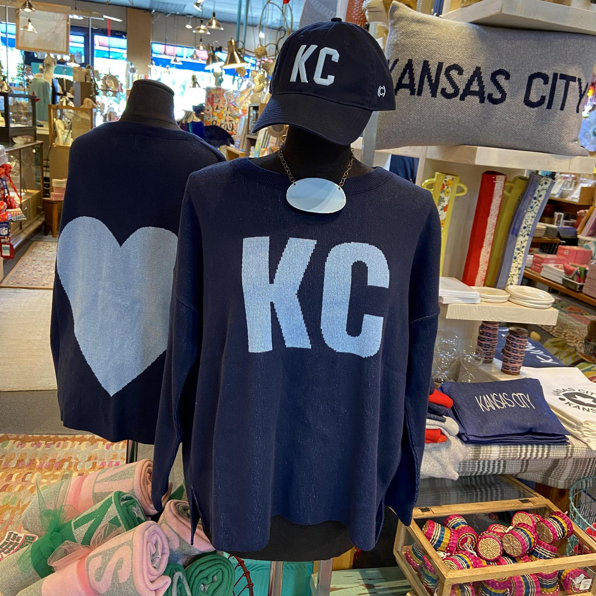 Navy sweatshirt with 'KC' and heart design in a store setting